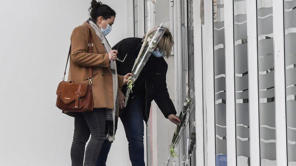 Two women bring flowers outside a branch of France's government job centre Pole Emploi in Valence on January 29,2021