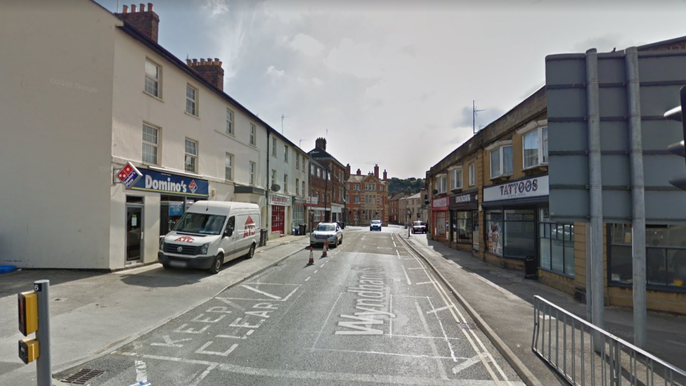 A road with several shops and four vehicles parked