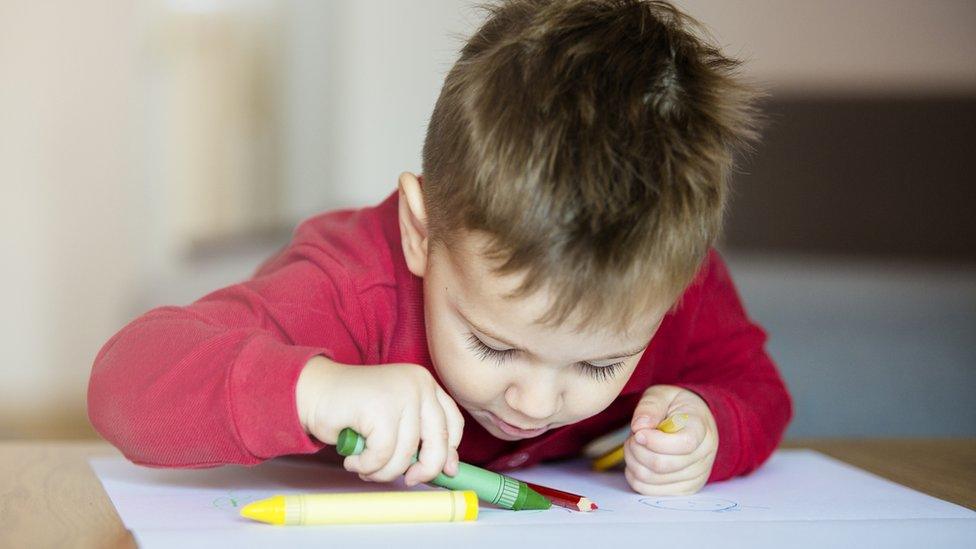 Young boy colouring in paper