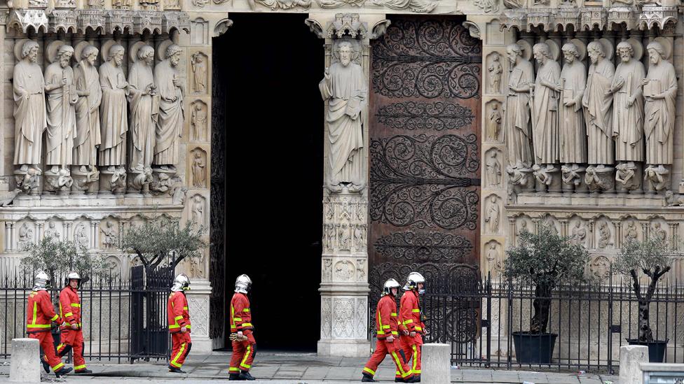 Firefighters walk in front of Notre-Dame