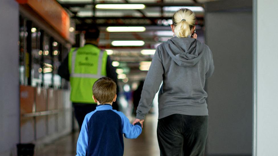 A refugee with a child walks at an accommodation centre for refugees, including Ukrainians, inside former airport Tegel in Berlin, Germany November 9, 2022