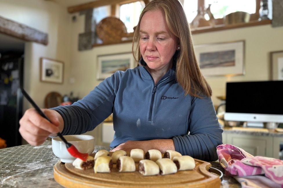 A woman brushes egg on to pastry