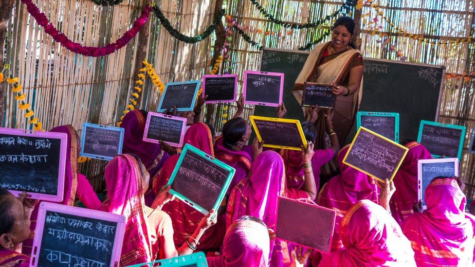 woman in class holding up chalkboards