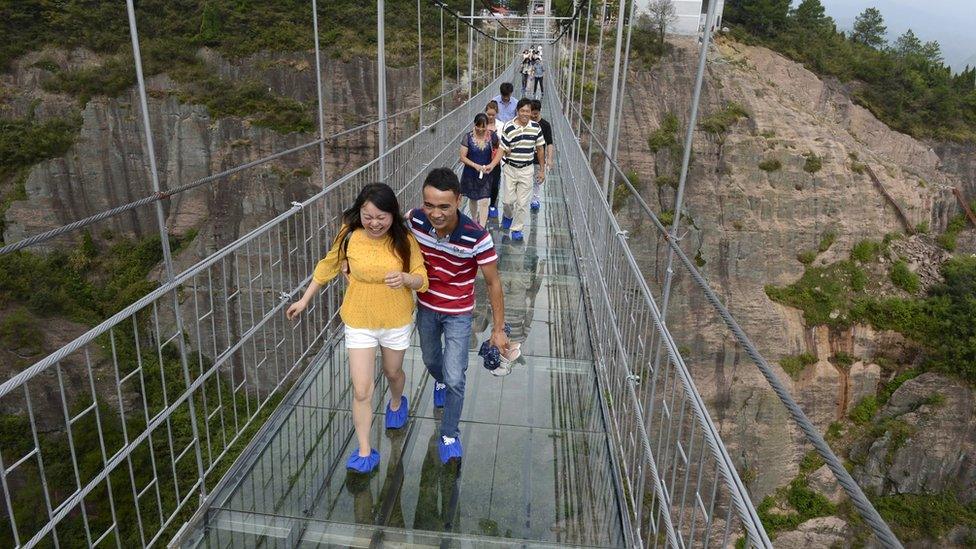 People crossing glass bridge in China