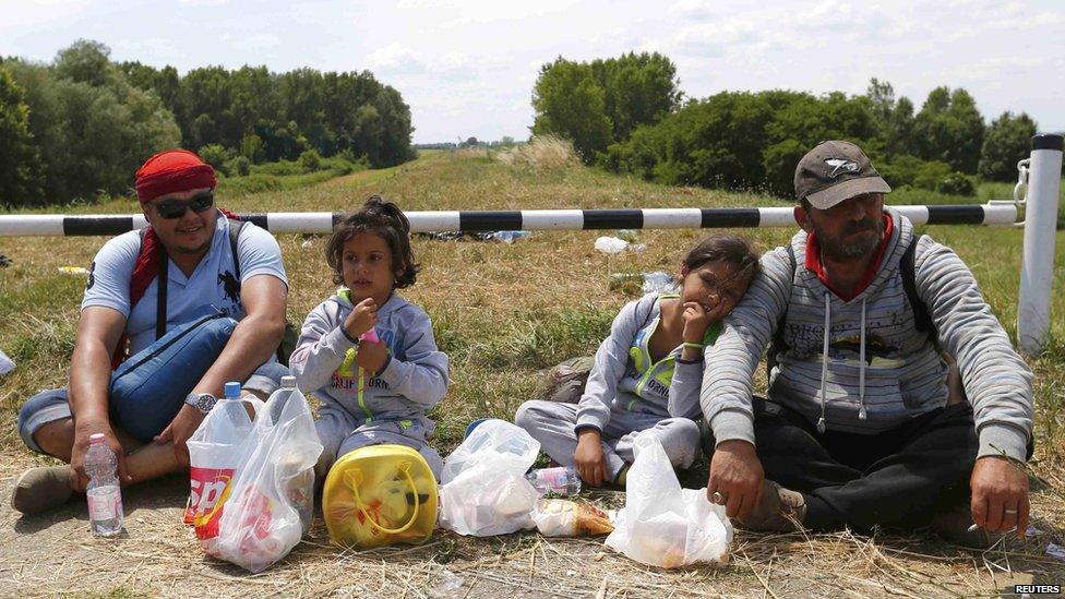 Migrants from Syria sit on a dam near Szeged, southern Hungary, 29 Jun 15