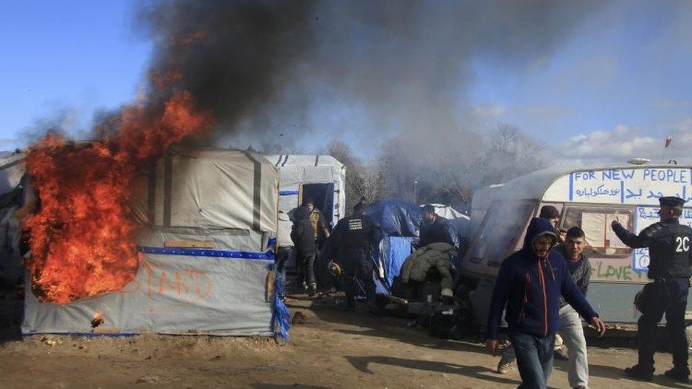 Smoke and flames rise from a burning hut in the Jungle camp in Calais