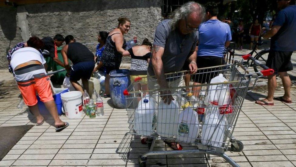 Residents gather water from a fire hydrant at a neighbourhood in Santiago, Chile, Monday, Feb. 27, 2017