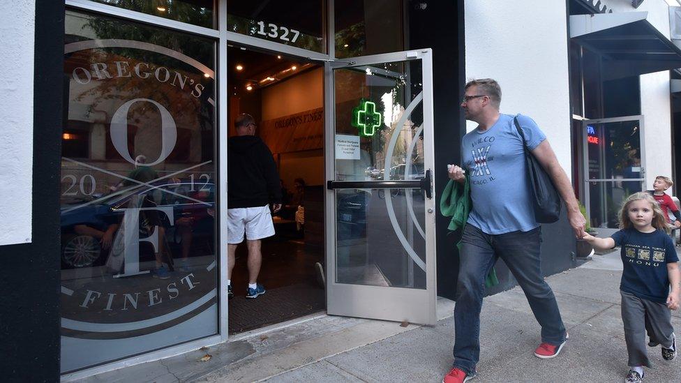 A man walks with his daughter near Oregon's Finest, a marijuana dispensary in Portland, Oregon, on October 4, 2015