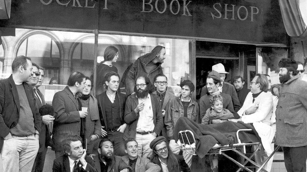 Lawrence Ferlinghetti outside his famous shop with Allan Ginsberg (beard and glasses) and other beats