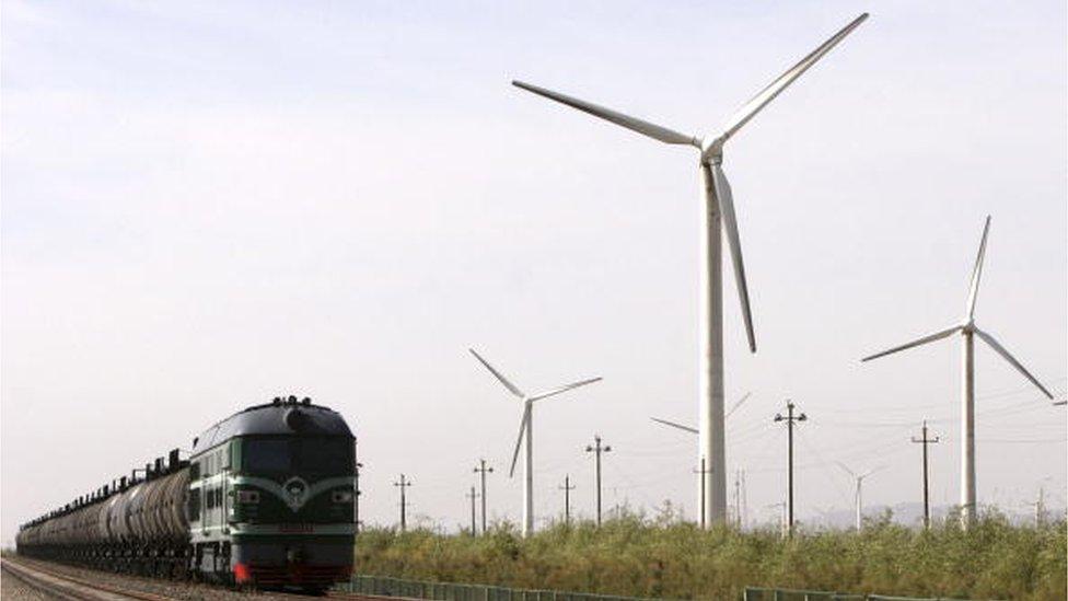 A train runs past wind turbines at a wind power plant in Dabancheng, Xinjiang Uygur Autonomous Region, China