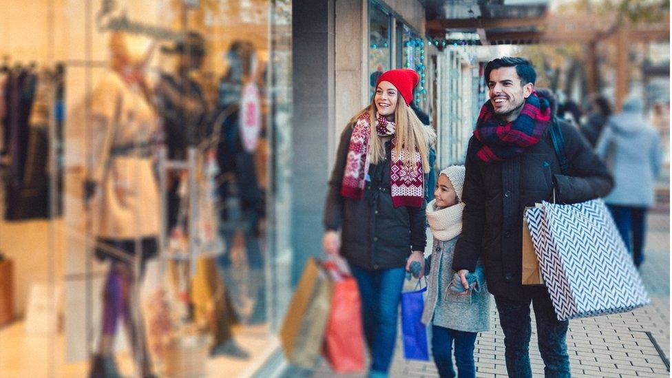 A family look at clothes through a shop window