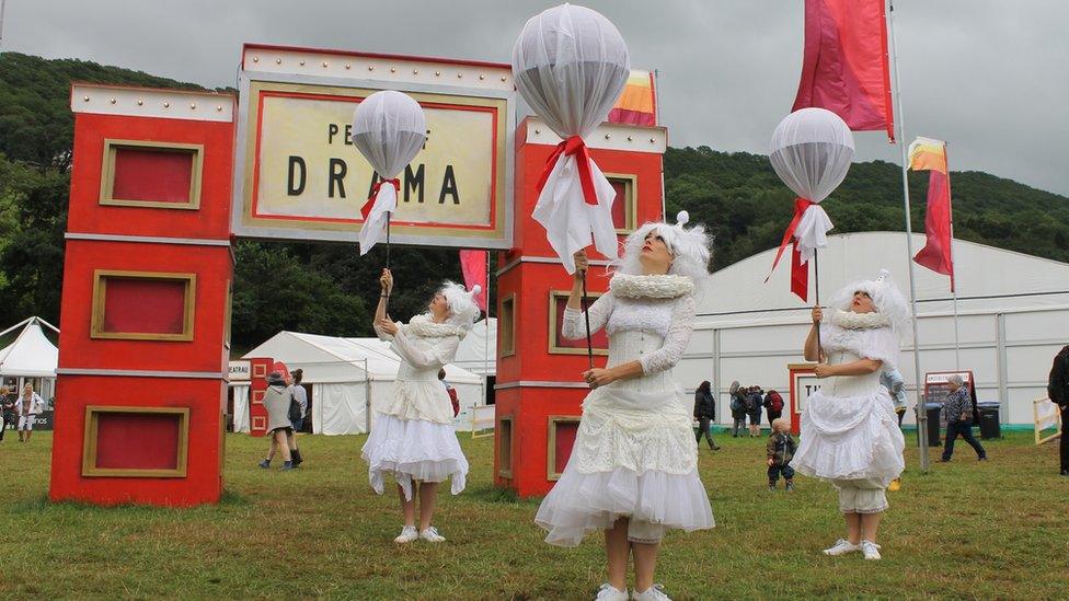 Tri pherson mewn gwisg wen a balŵn mewn 'perfformiad stryd' ar y Maes // Three street performance dressed in white with balloons