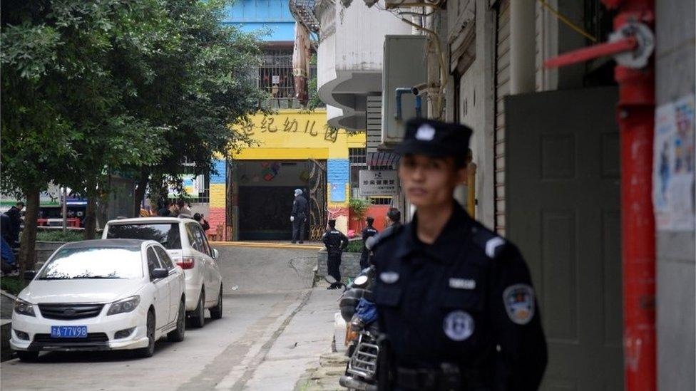 Police officers stand in the street outside the Chongqing kindergarten