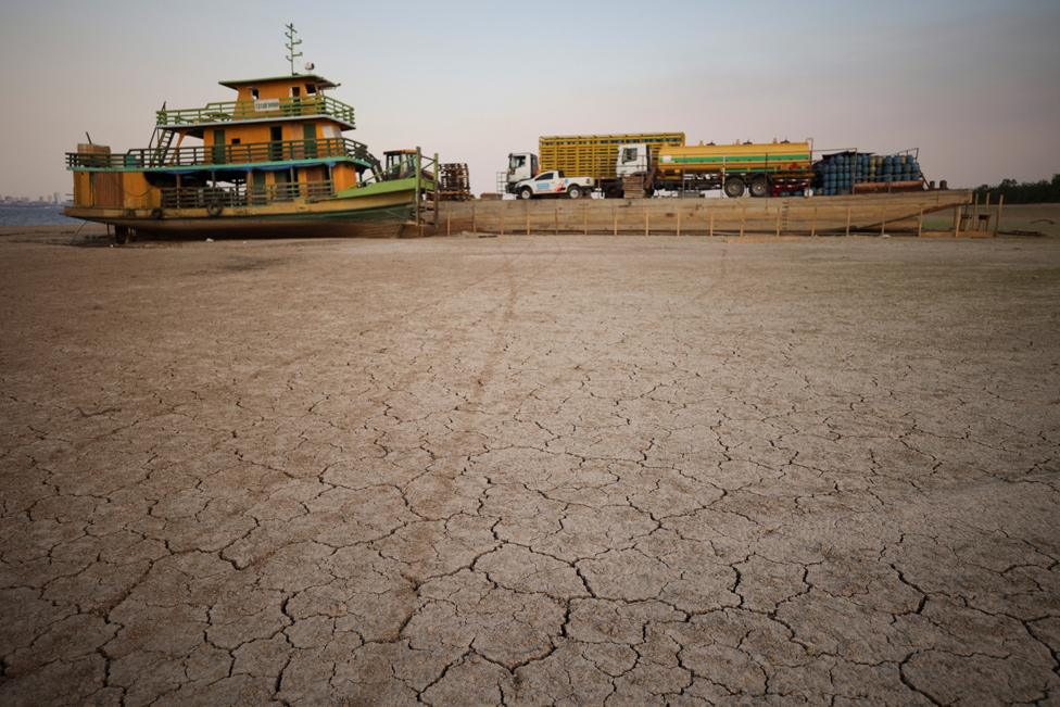 A tug boat and a barge carrying three trucks, 2,000 empty cooking gas cylinders stranded on a sand bank of a diminished Rio Negro river after running aground last month, as the region is hit by a severe drought, in Cacau Pirera, Brazil October 10, 2023.