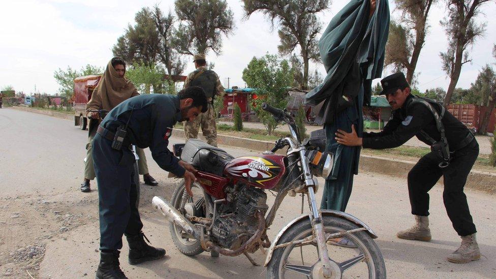 In this photograph taken on 23 March 2017, Afghan policemen search passengers at a checkpoint in Lashkar Gah