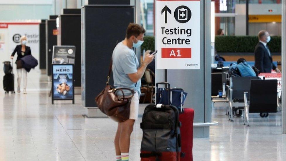 Passengers standing near a sign for Covid-19 testing at Heathrow Airport