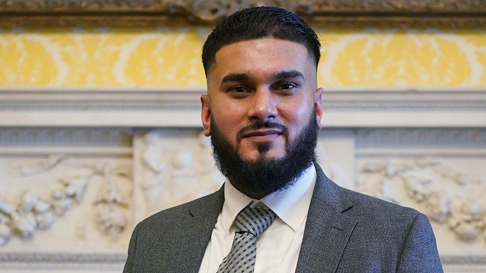 Rizwan Javed head and shoulders portrait, he has short hair, a beard and wearing a suit and tie