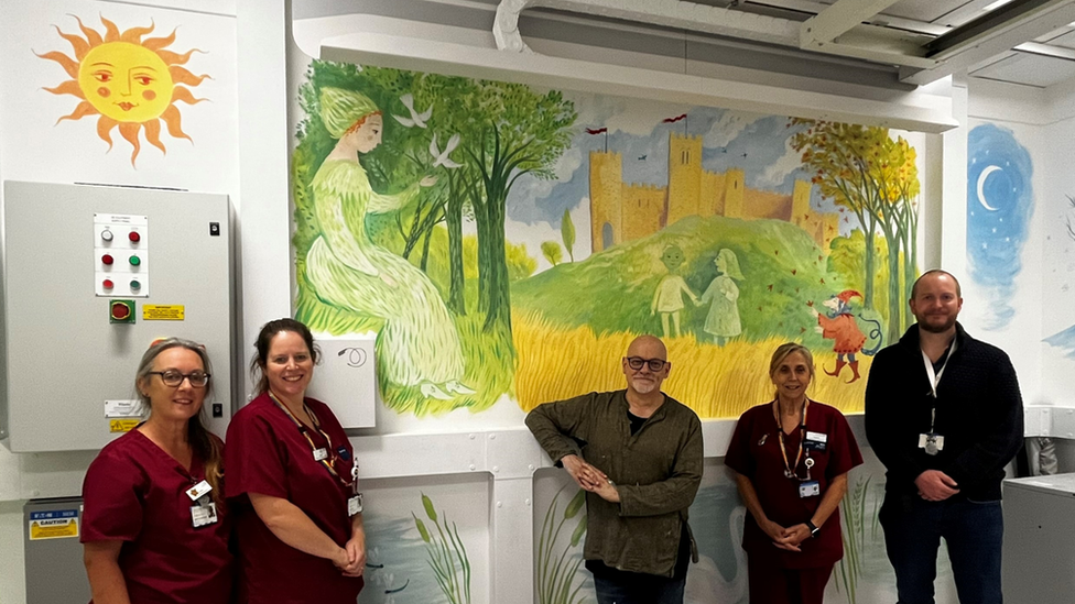 West Suffolk Hospital staff members and James Mayhew in front of the mural