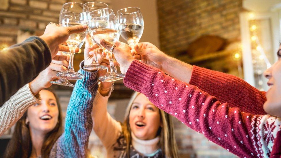 People in Christmas jumpers raise their glasses