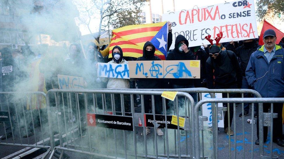 Catalan pro-independence protesters stand behind crowd control barricades during a demonstration in Barcelona on December 21, 2018