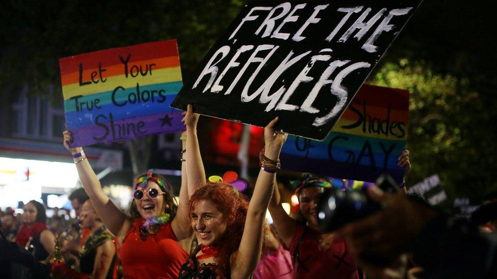 Marchers with political statements on refugees detained by Australia"s government hold signs during the annual Sydney Gay and Lesbian Mardi Gras parade in Sydney, Australia March 4, 2017. The signs read "freee the refugees" and "let your true colours shine"