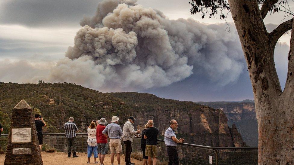 Tourists at a vantage point in the Blue Mountains look at huge smoke clouds from a bushfire