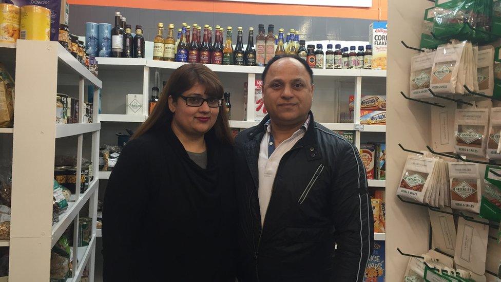 A man and a woman stand together in a food shop