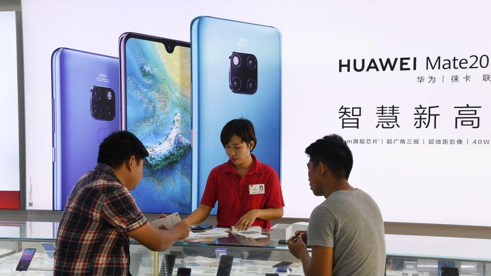 A store clerk serves customers at a Huawei store