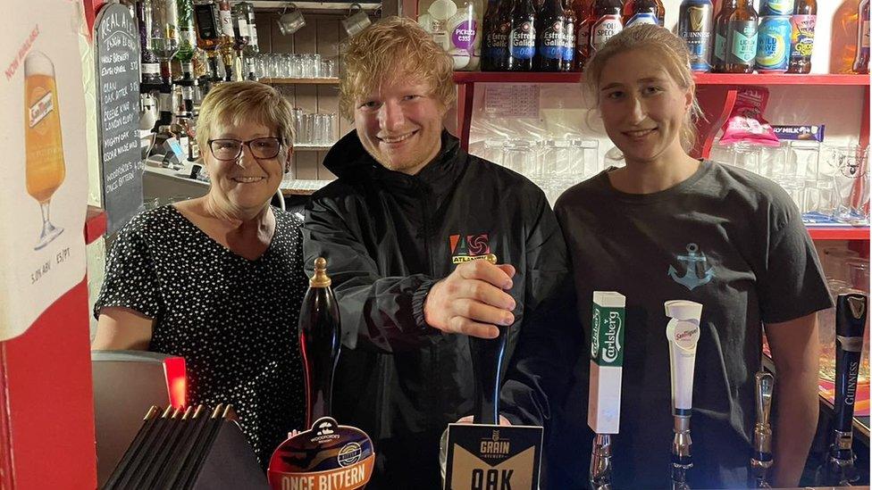 Ed Sheeran behind the bar at The Rumburgh Buck, with landlady Stella Cattermole and another staff member