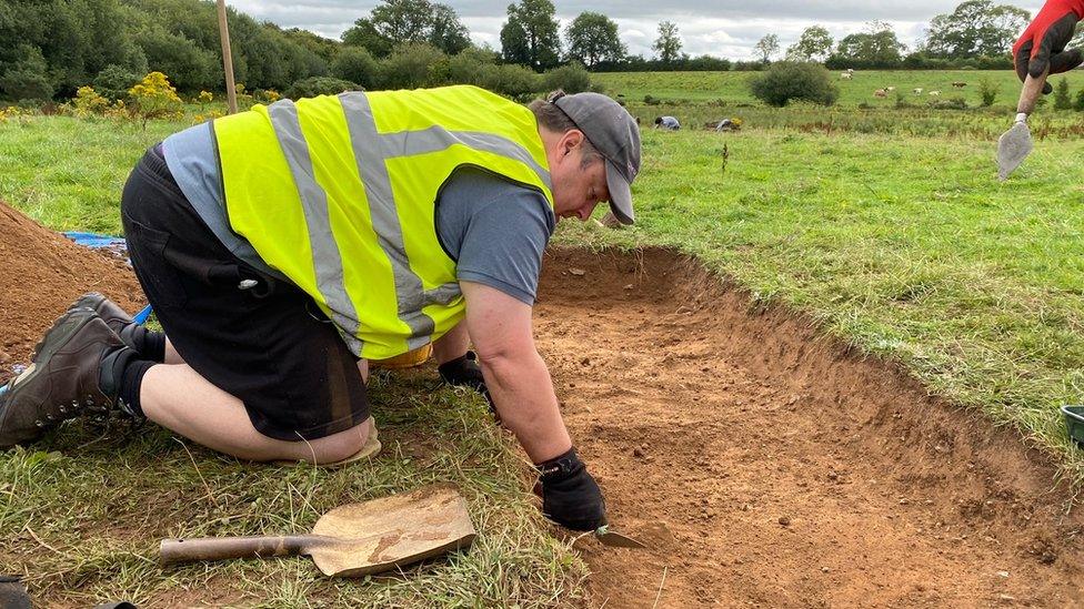 Volunteer Daniel digging in a trench