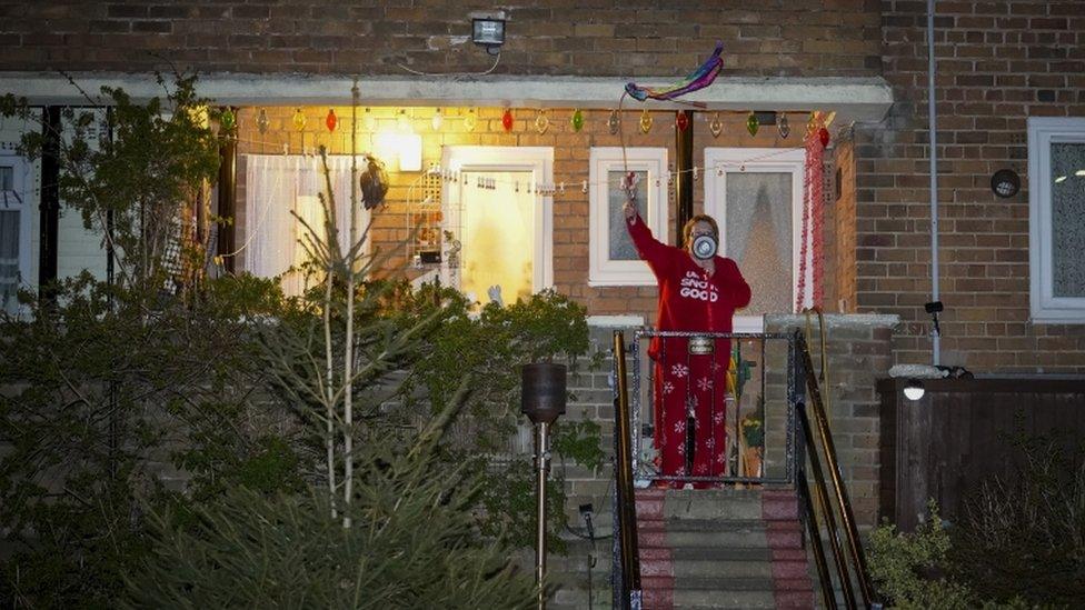 A resident across the road from Wythenshawe Hospital in Manchester joins in the national salute to healthcare workers