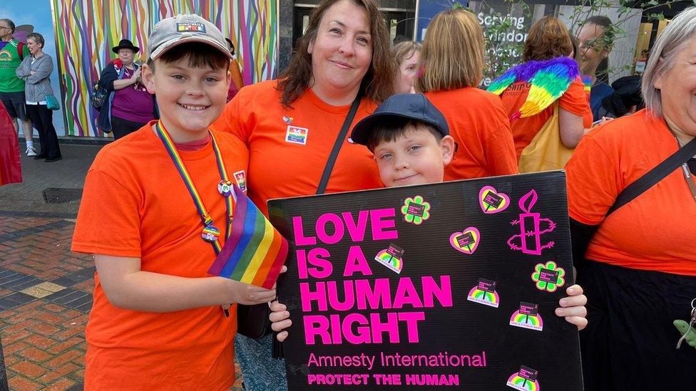 A boy holding a sign reading "love is a human right"