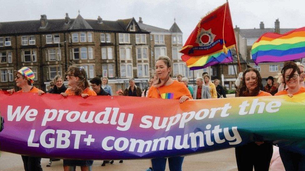 People holding a rainbow banner in Pride parade