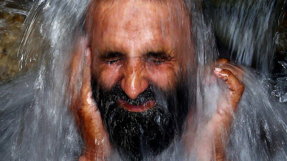 Man cooling off under water supply pipe