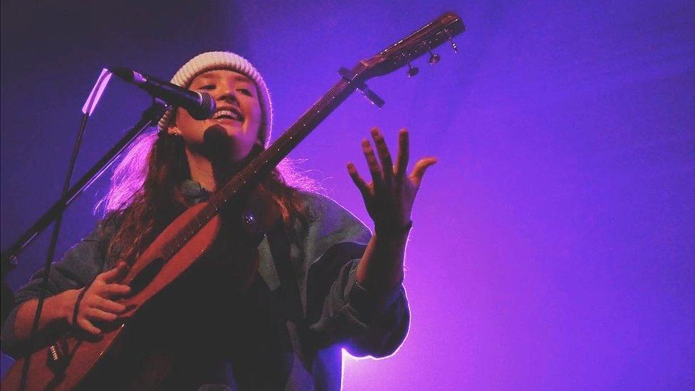 Kyla Stroud playing a guitar on stage