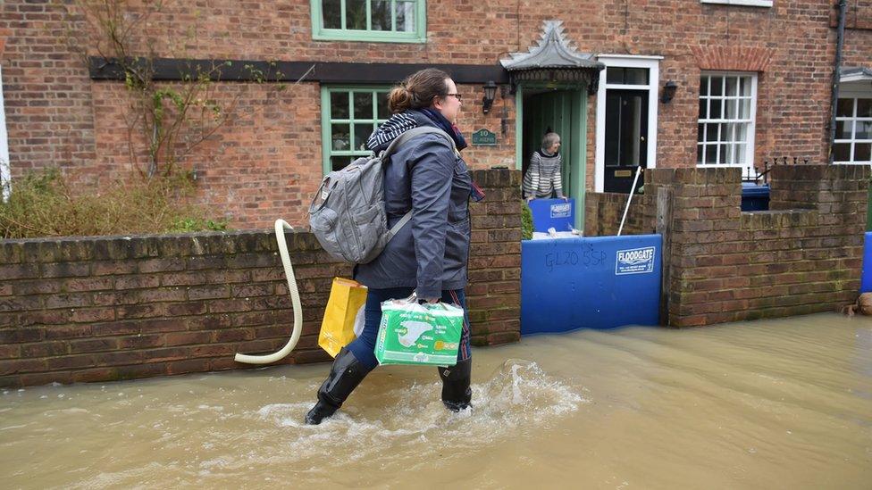 A woman wading through floods in Tewkesbury, Gloucestershire