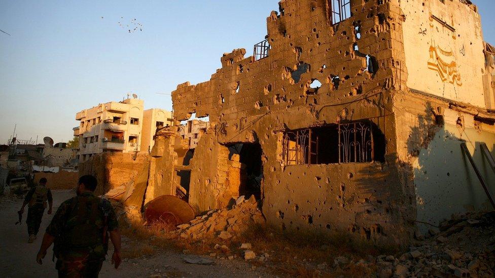 Rebels walk past damaged buildings in Jobar, a suburb of Damascus, Syria (6 September 2016)