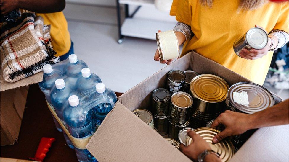 Boxes of tinned food and packets of water bottles at a food bank