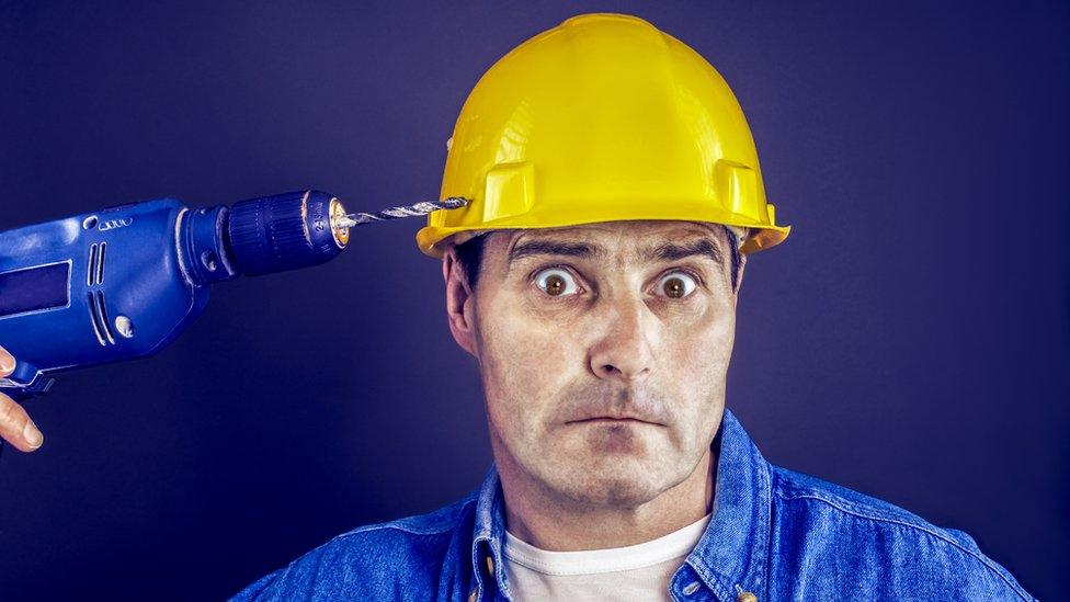 Workman pointing drill at his hard hat