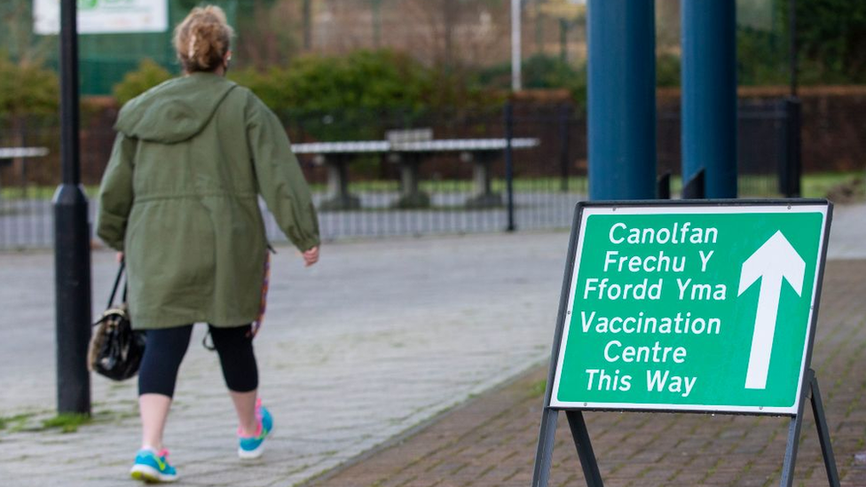 Woman walking past vaccination centre sign in Merthyr Tydfil