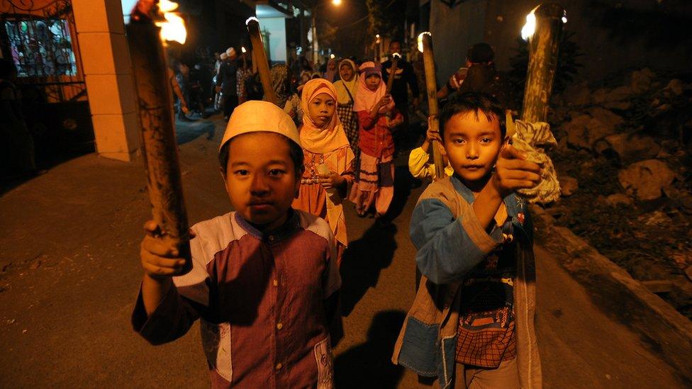 Children in Indonesia carry torches in a parade through the street to celebrate Eid al-Adha.