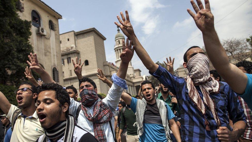 Egyptian students, supporters of the Muslim Brotherhood and Mohammed Morsi, flash the four-finger "Rabaa" symbol, as they demonstrate outside Cairo University on 9 April 2014