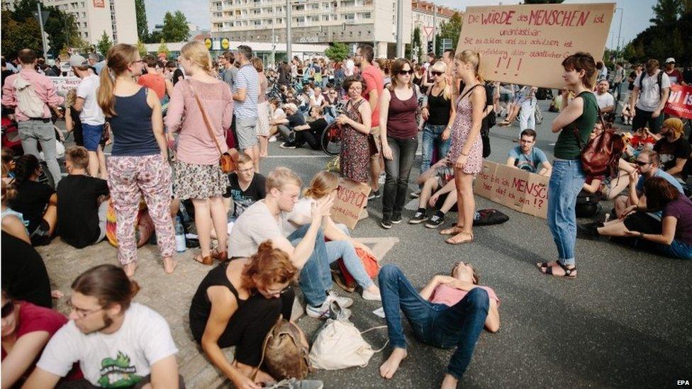 Demonstrators with banners sit in the inner city of Dresden