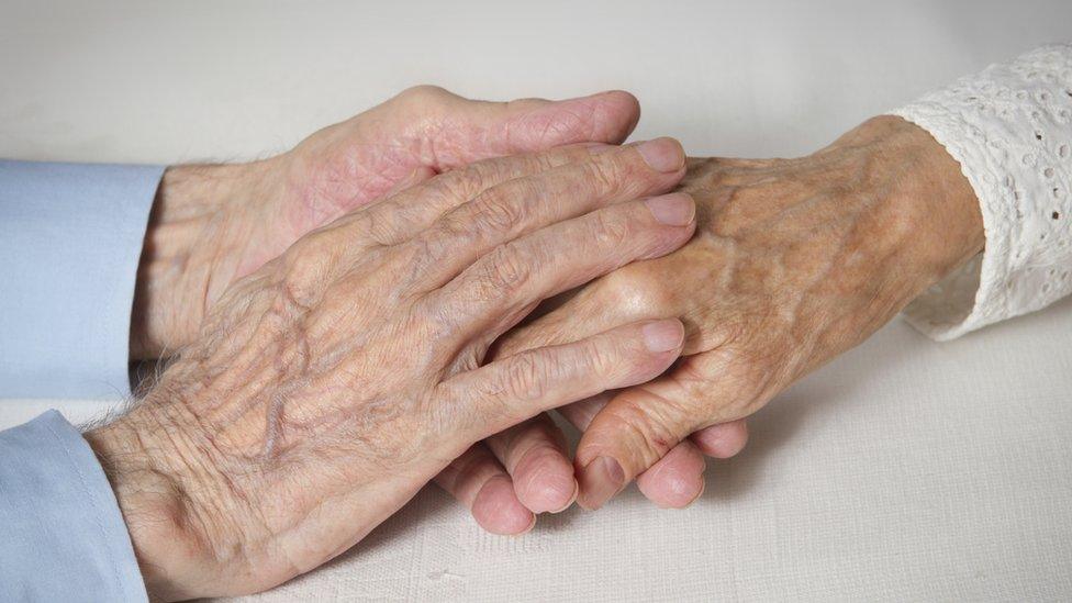 elderly couple holding hands