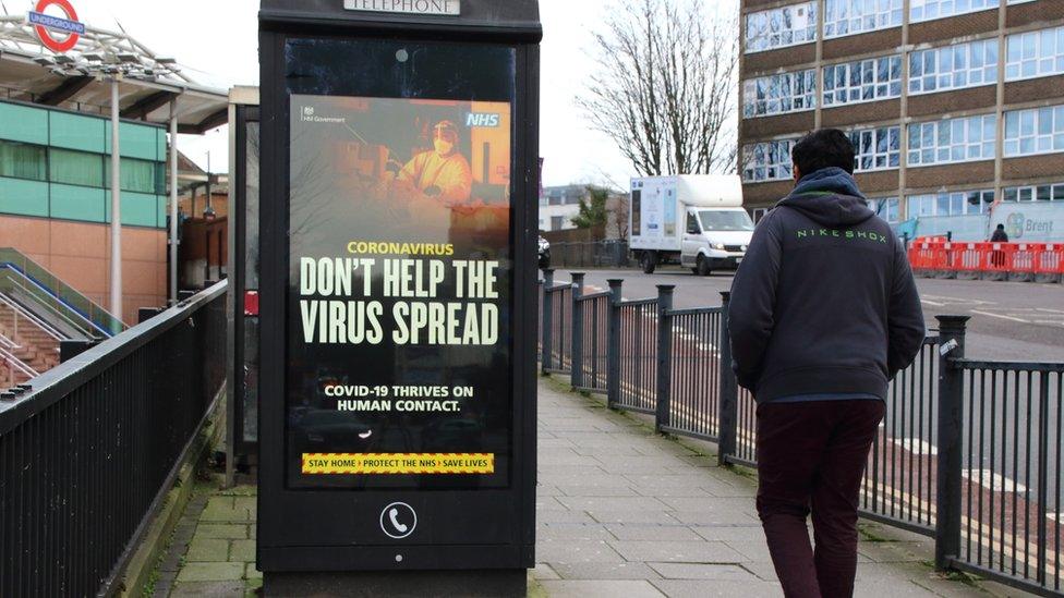 A person walks past a Covid-19 warning sign