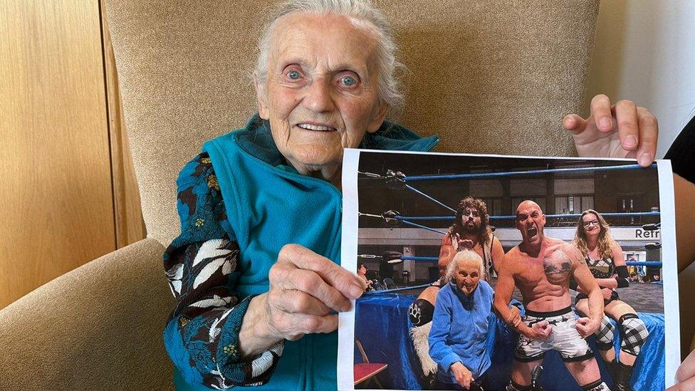 Jane Prosser holding a picture of her with some wrestlers