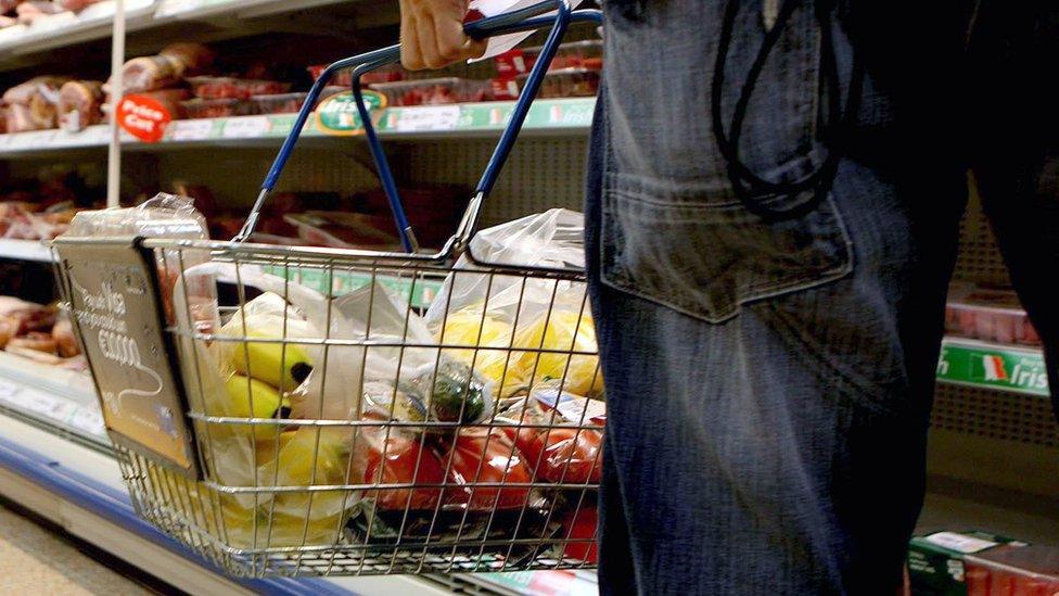 A person holding a shopping basket in a supermarket