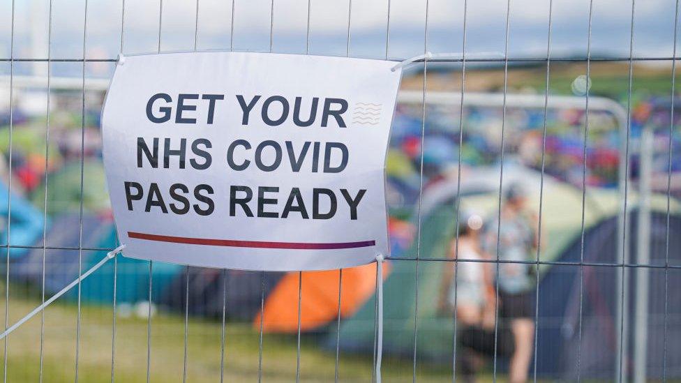 Covid pass sign on metal fence at a festival