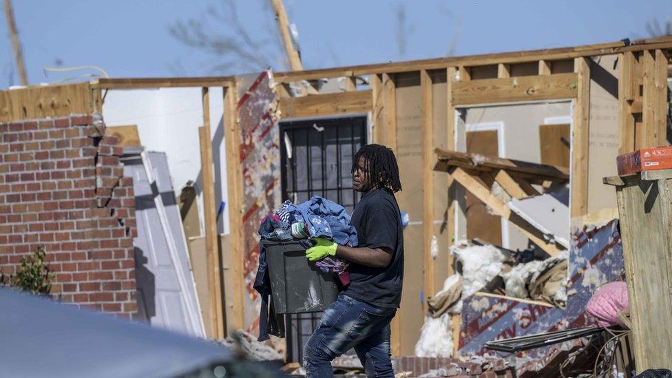 People collect clothing from their damaged homes