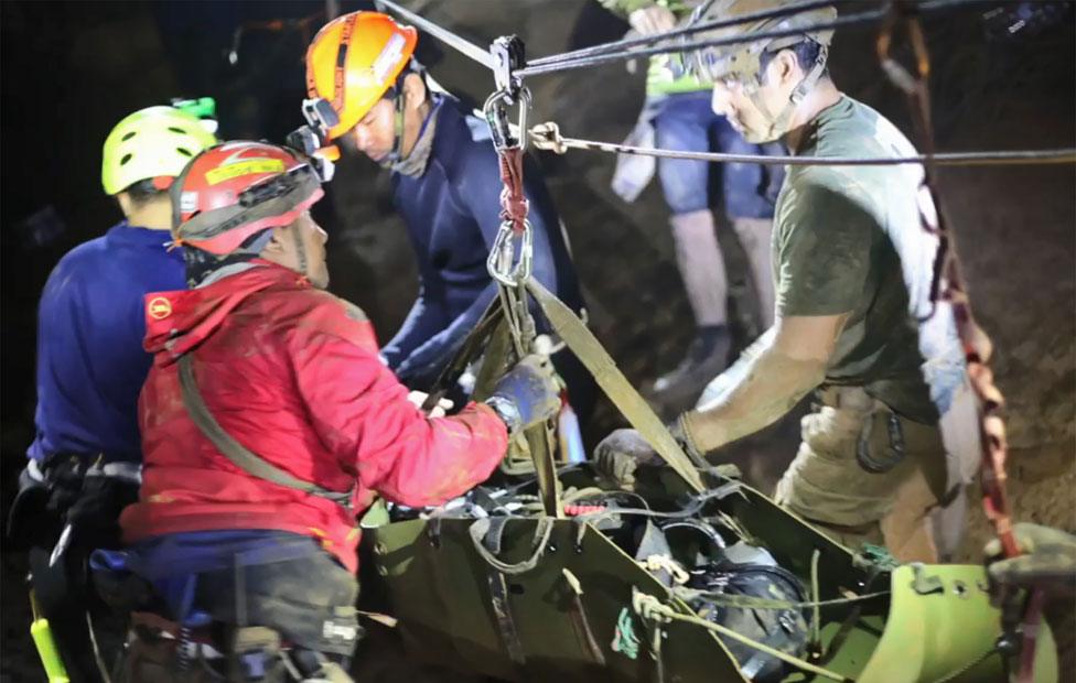 Boy being moved by rescuers inside the cave